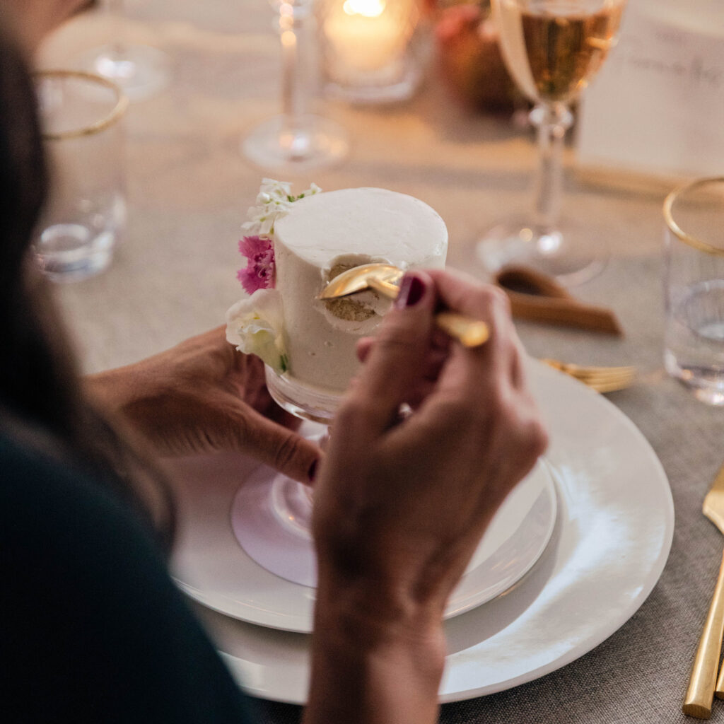 A guest enjoying a personal-sized wedding cake, elegantly plated and decorated with flowers.